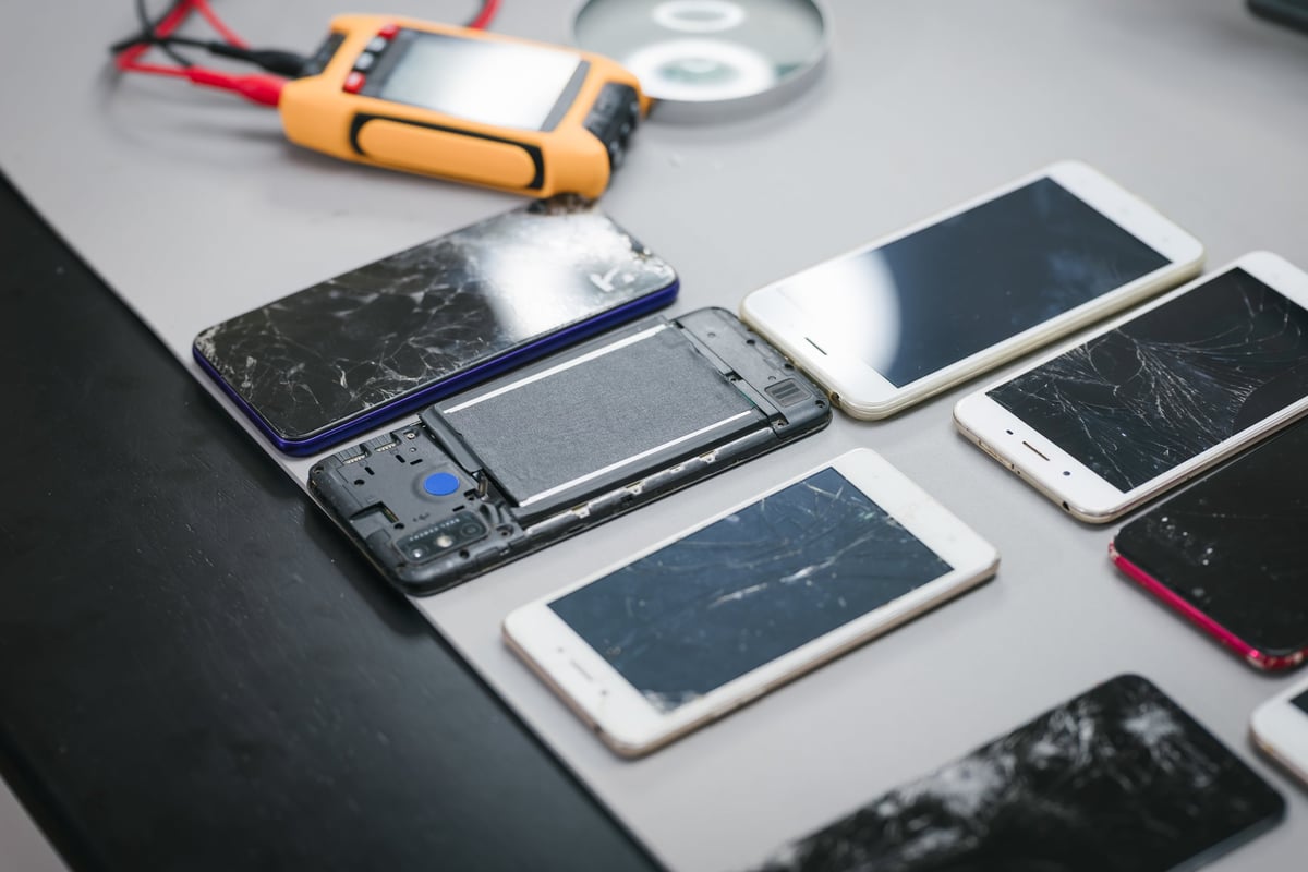 Defekte Smartphones mit gesprungenem Display auf dem Reparaturtisch bei ONEREPEX in Rosenheim